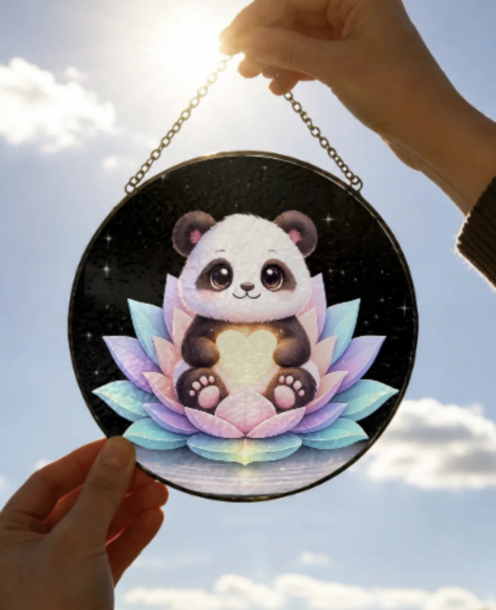 Circular Suncatcher with a panda design held against a sky background